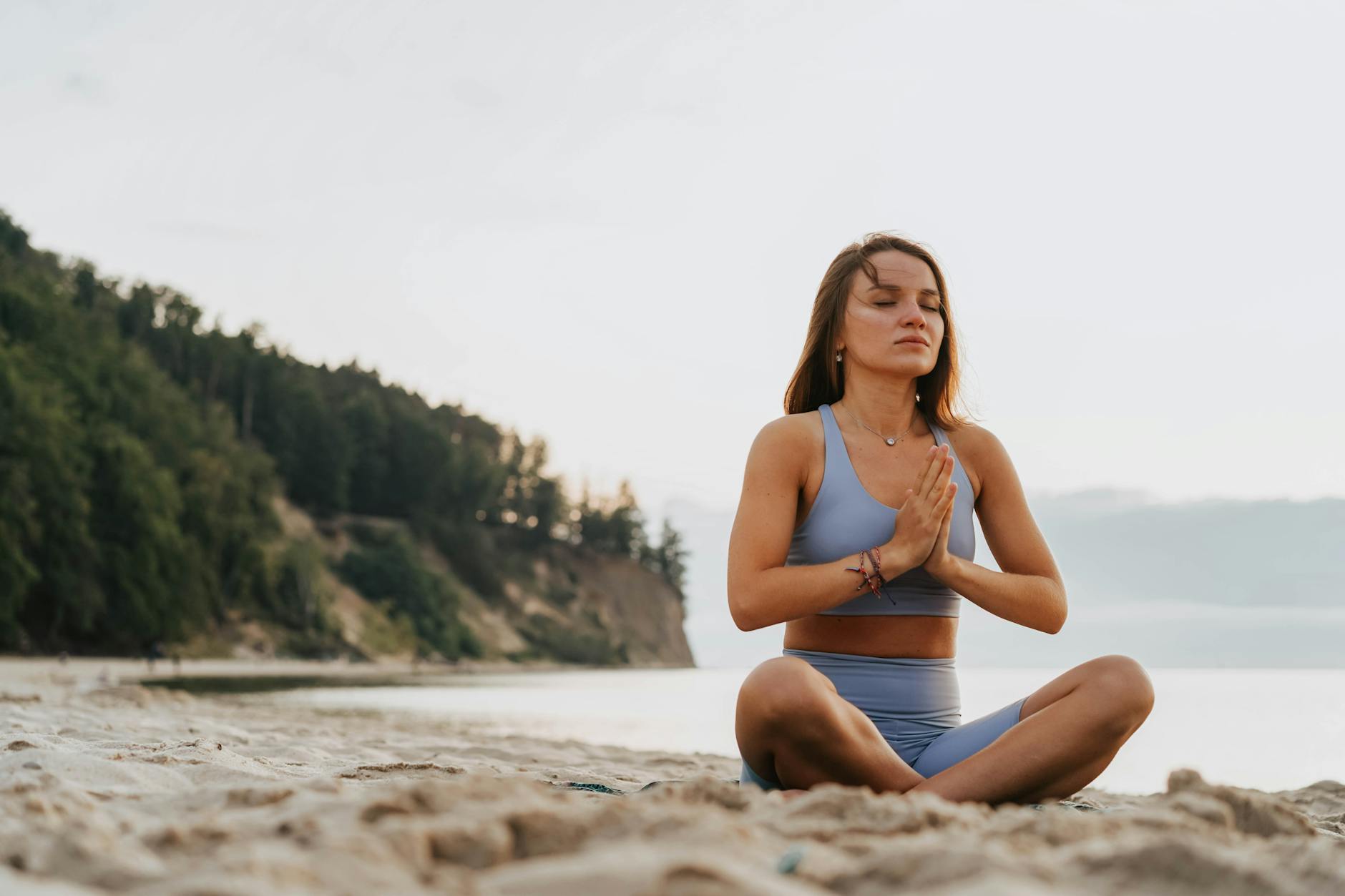 a woman building her coastal sport and wellness doing a meditation on a beach during morning